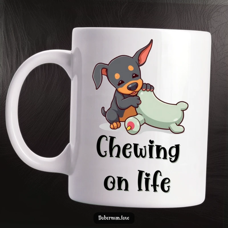 Funny mug showing a tiny Doberman playfully wrestling with an oversized toy chew, highlighting its determined and energetic spirit.