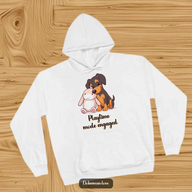 Funny Doberman nudging a big plush toy on a warm hoodie, a hilarious and cozy gift for dog lovers.