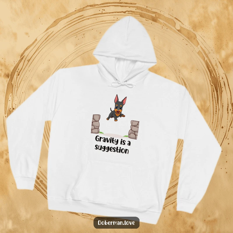 Funny hoodie design of a small Doberman puppy mid-wobbly jump over a small gap, capturing a moment of cute effort and concentration.
