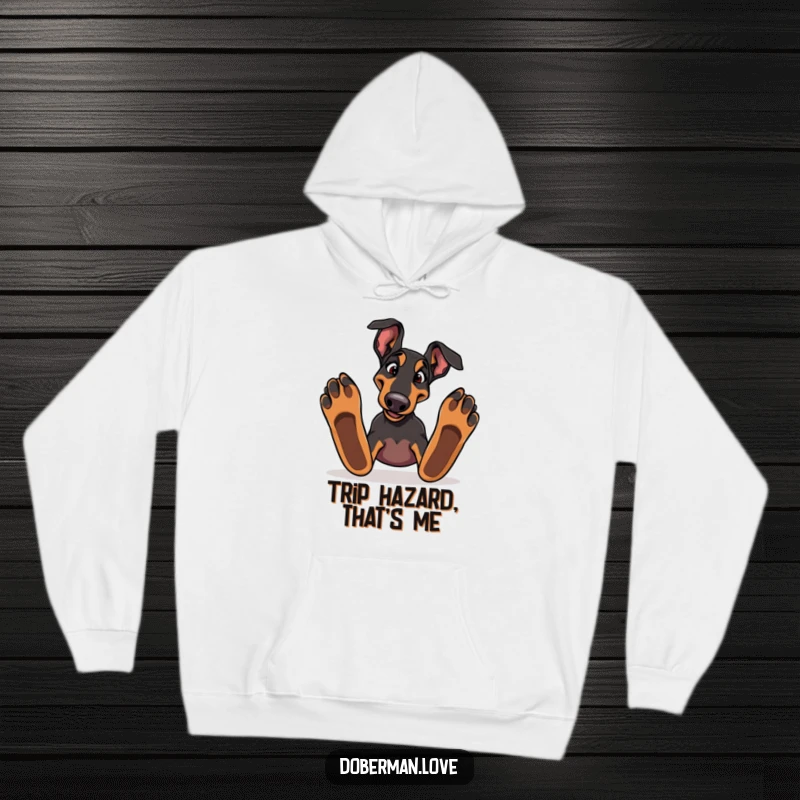 Silly Doberman dog tripping over its paws on a soft hoodie, embodying playful canine clumsiness.