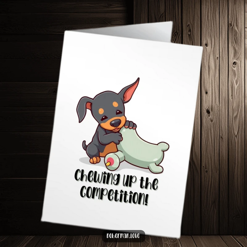 Free Printable Congratulations Card: A tiny Doberman enthusiastically wrestles with an oversized toy chew, celebrating their win.