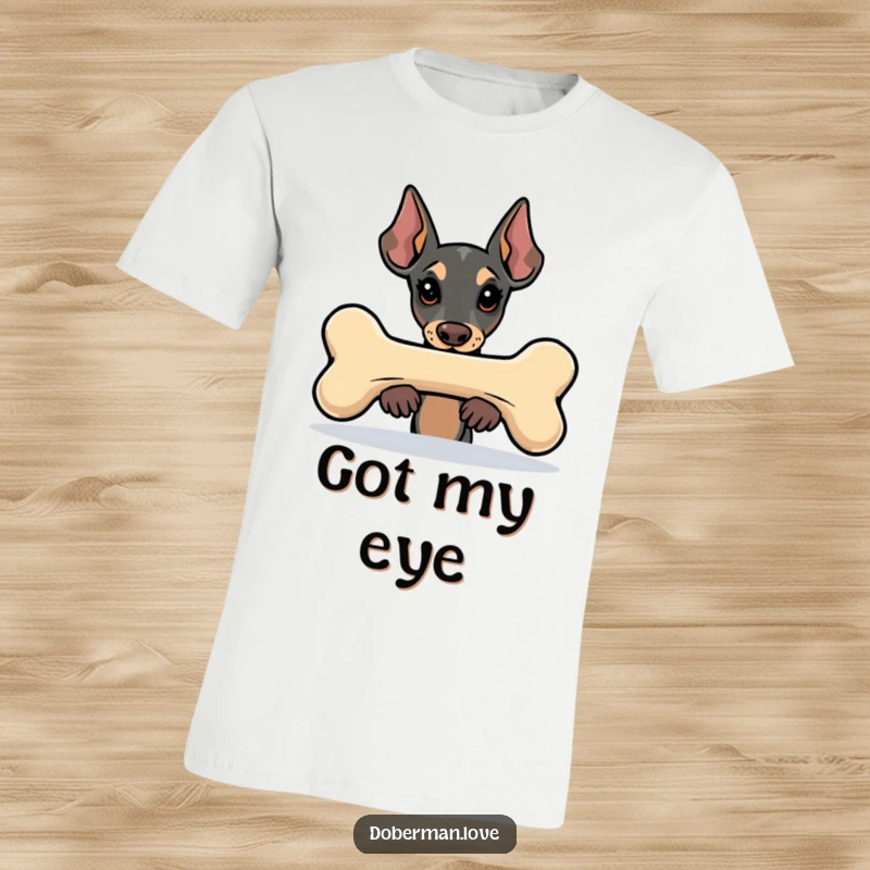 Funny Kawaii Doberman t-shirt with a charming dog peeking from behind a very large, stylized bone, conveying curiosity and fun.